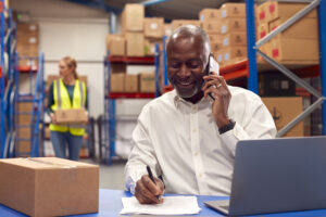 Male Team Leader Working On Laptop Talking On Mobile Phone