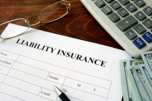 reduce employers' liability insurance concept. Form with Liability Insurance at top beside computer keyboard