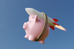 Piggy bank with rocket on grey background