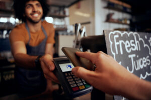 Customer using smartphone to pay in cafe, card payment machine concept
