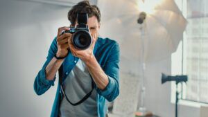 Fashion photographer in studio taking photograph of viewer, examples sole traders concept
