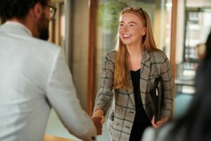 Inductions hybrid staff concept. Young redheaded woman shaking hands with colleague